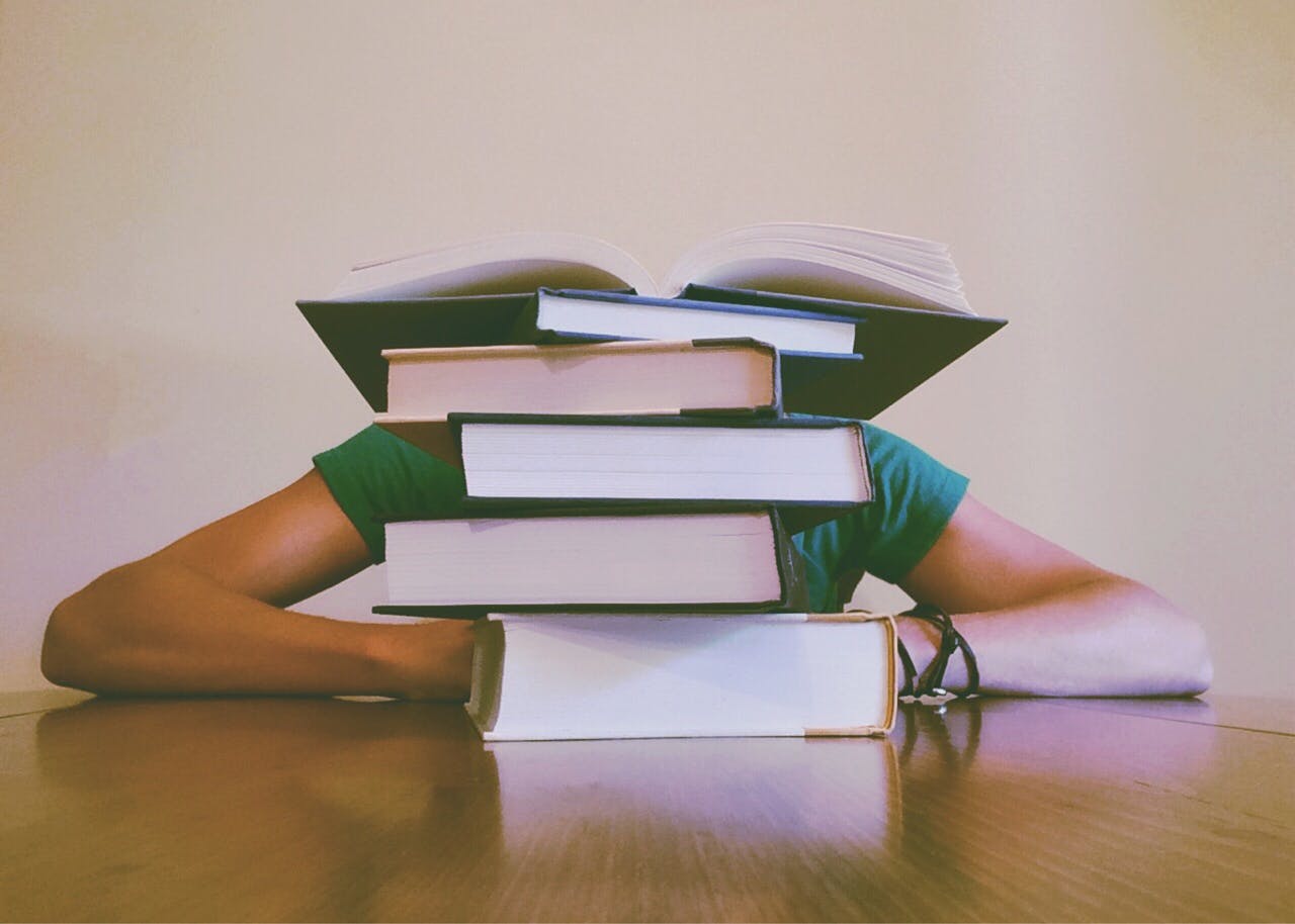 Student with head down and pile of books