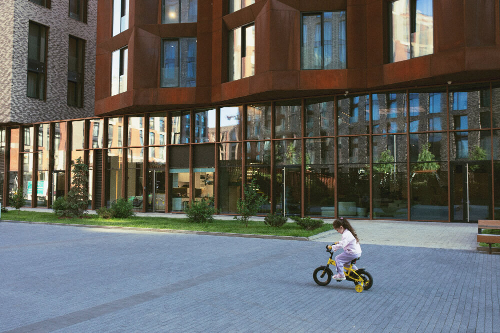 kid riding bikes past modern development